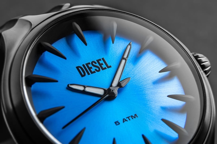 Niebieska metaliczna tarcza zegarka Diesel DZ2203 z czarnymi indeksami i białymi wskazówkami.